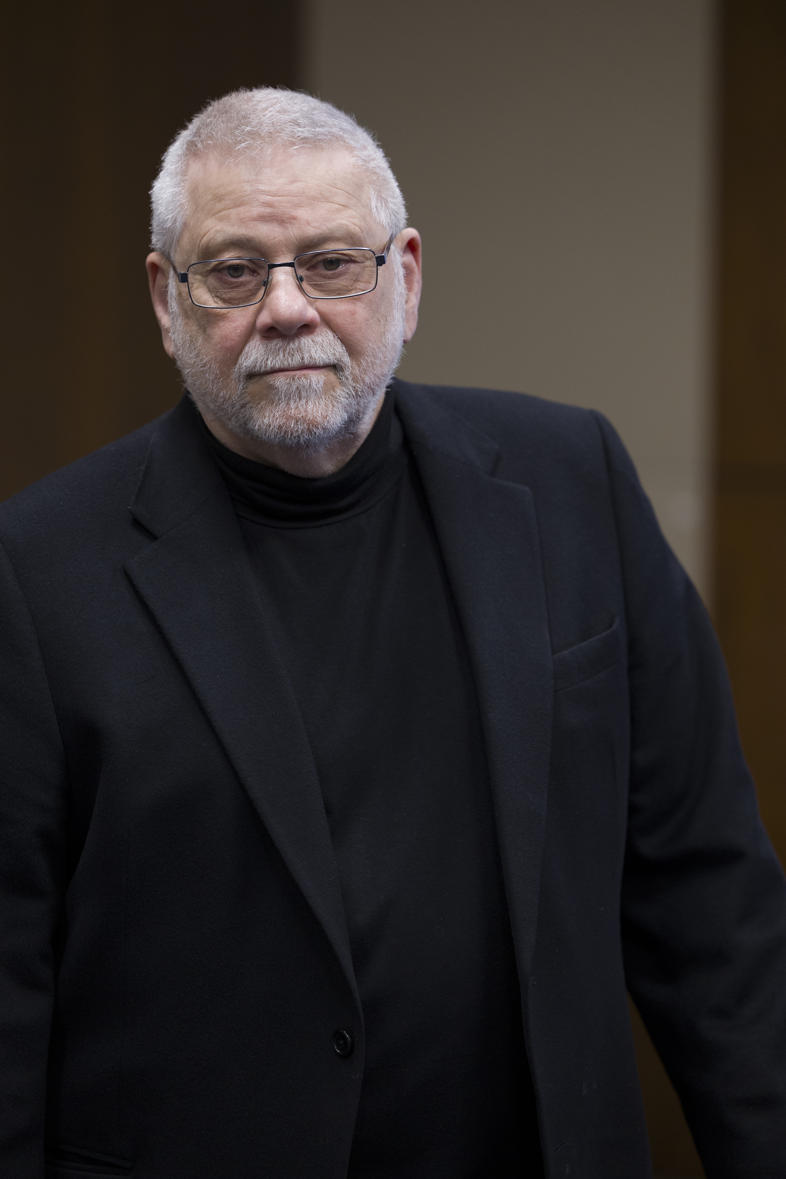 Ed at podium, glasses, somber