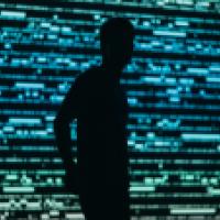 Surveillance, illustrated by the silhouette of a man in front of a data wall